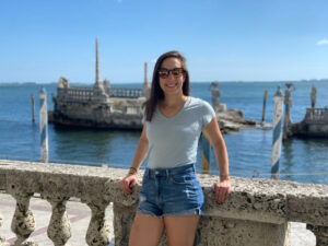 Picture of me in a blue shirt and blue jean shorts by the water at the Vizcaya Museum