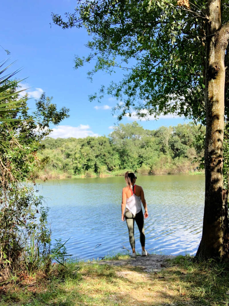 Me standing on the edge of a lake with my back to the camera, taking a break while hiking in Florida 