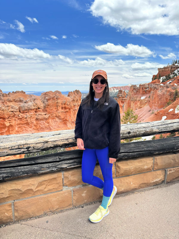 Me smiling next to the railing. Bryce Canyon in the background.