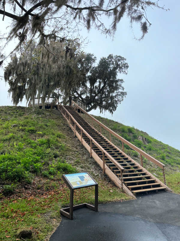 Stairs to climb the mound and a park informational sign.