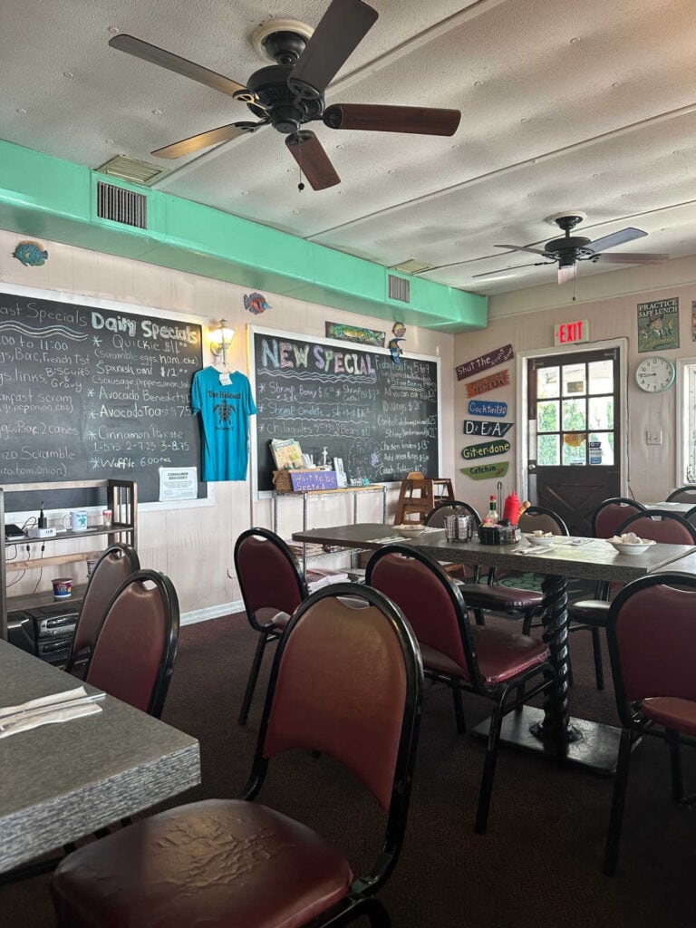 Empty tables and chairs with specials listed on the wall.